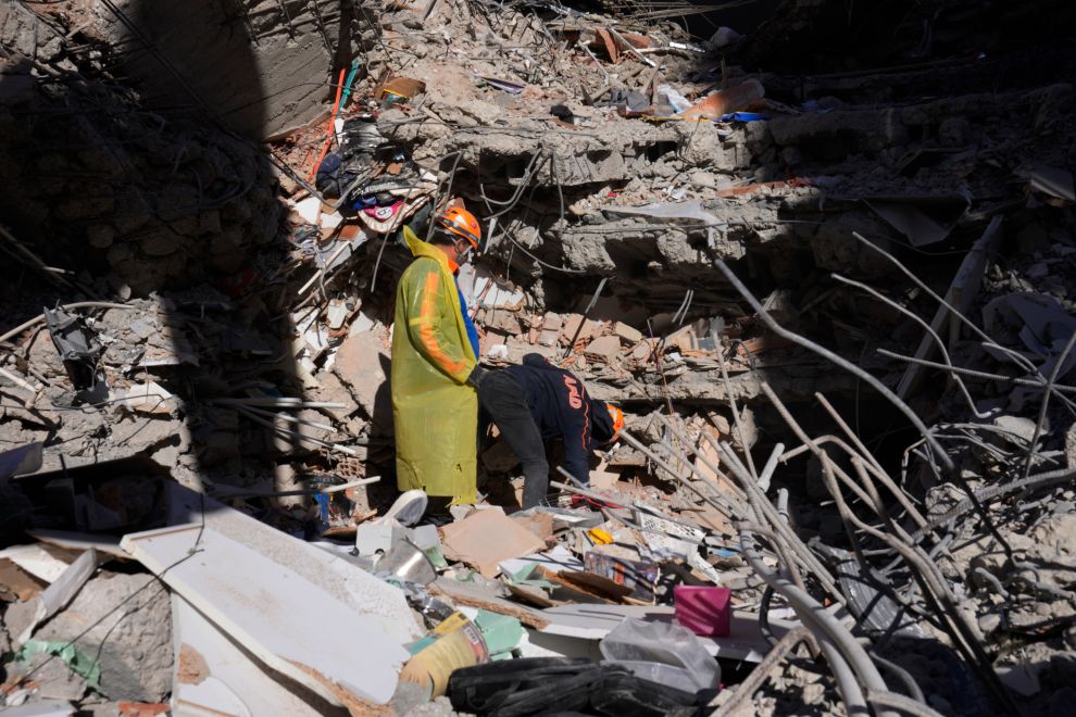 Emergency teams search for people in the rubble of a destroyed building in Adana, southern Turkey, Tuesday, Feb. 7, 2023. A powerful earthquake hit southeast Turkey and Syria early Monday, toppling hundreds of buildings and killing and injuring thousands of people. (AP Photo/Hussein Malla)